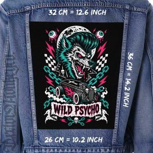 Pode incluir: Um emblema retangular de tecido numa jaqueta jeans azul com um lobisomem de topete, um hot rod em forma de caixão, correntes e caveiras. O texto diz WILD PSYCHO. As dimensões são 32 cm por 36 cm, com uma base de 26 cm.
