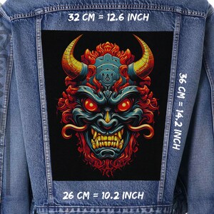 May include: A denim jacket with a black patch featuring a colorful illustration of a Japanese demon with red eyes and sharp teeth. The patch is 12.6 inches wide, 14.2 inches tall, and 10.2 inches deep.