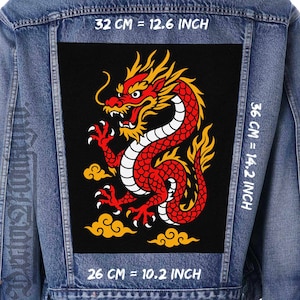 Könnte beinhalten: Jeansjacke mit einem großen schwarzen Aufnäher mit einem rot-gelben Drachendesign. Der Drache ist mit weißen Akzenten versehen und sitzt über gelben Wolkenformen. Der Aufnäher misst 32 cm breit, 36 cm hoch und 26 cm quer.