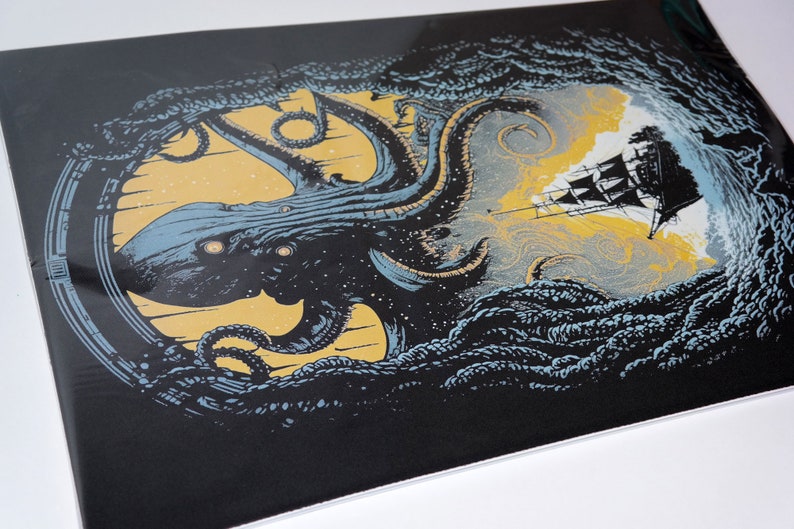 May include: A print featuring a kraken attacking a ship, rendered in black, blue, and yellow. The kraken has glowing eyes, and the ship is black and white. The background is yellow, and the print is framed by a dark border.