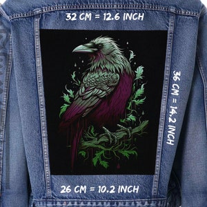 Op de afbeelding: Een zwart denim jack met een grote, kleurrijke patch van een raaf op de rug. De patch is 32 cm breed, 36 cm hoog en 26 cm diep. De raaf is afgebeeld in een donkerpaarse, groene en zwarte kleurstelling.