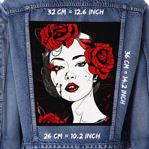 Könnte beinhalten: Eine Jeansjacke mit einem schwarzen Patch, der eine Frau mit roten Rosen im Haar zeigt. Der Patch hat den Text "32 CM = 12.6 INCH", "36 CM = 14.2 INCH" und "26 CM = 10.2 INCH" aufgedruckt.