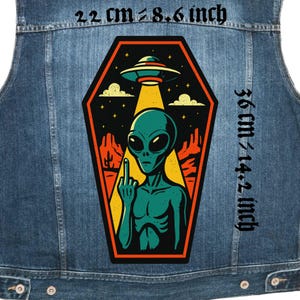 May include: A denim vest featuring a large, colorful patch with an alien design. The patch, measuring 8.6 inches wide and 14.2 inches tall, depicts a green alien giving the middle finger under a UFO and desert landscape.