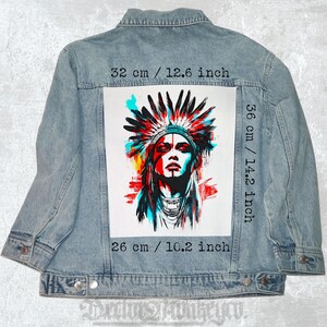 May include: Light blue denim jacket featuring a vibrant graphic of a Native American person with a headdress. The graphic is 12.6 inches wide and 14.2 inches tall, with a base of 10.2 inches. The jacket has a classic design with button closures.