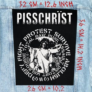 May include: A black patch with the text "PISSCHRIST" in white, above a circular graphic with figures and text. The patch is on a light blue denim jacket. The patch measures 12.6 inches by 14.2 inches.