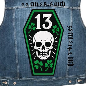 Peut inclure: Un gilet en jean avec un grand écusson représentant un crâne blanc, le chiffre 13 et des trèfles verts. L'écusson est en forme de cercueil, avec des dimensions de 22 cm x 36 cm (8,6 pouces x 14,2 pouces).