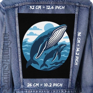 Può includere: Giacca di jeans blu con una grande toppa raffigurante una balena blu e il suo cucciolo in una scena marina. La toppa misura 32 cm di larghezza e 36 cm di altezza, su sfondo nero all'interno di un cerchio bianco. Giacca di jeans.
