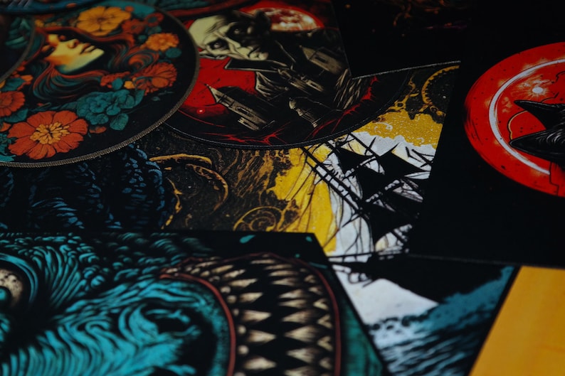 K&ouml;nnte beinhalten: Eine Sammlung bunter gestickter Patches mit verschiedenen Designs, darunter eine Frau mit Blumen, ein Sch&auml;del, ein Schiff und ein Monster. Die Patches befinden sich auf einem schwarzen Hintergrund.