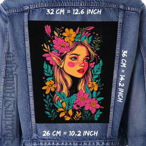 May include: A denim jacket with a large, rectangular patch featuring a colorful illustration of a woman with elf-like ears, surrounded by flowers. The patch measures 32 cm wide, 36 cm high, and 26 cm long.