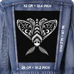 Peut inclure: Veste en jean avec un grand écusson noir orné d'un motif de papillon blanc. Le papillon a des motifs d'ailes complexes et une tête en forme de crâne. L'écusson mesure 32 cm sur 36 cm.