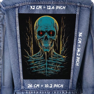 May include: A blue denim jacket with a black patch featuring a blue and green skull with red eyes. The patch is 32 cm wide, 36 cm tall, and 26 cm deep. The text "32 CM = 12.6 INCH", "36 CM = 14.2 INCH", and "26 CM = 10.2 INCH" is printed on the jacket.