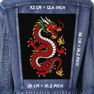 May include: A denim jacket with a large black patch featuring a red, yellow, and white dragon design. The patch measures 32 cm wide by 36 cm high, and 26 cm in length. The text "32 CM = 12.6 INCH", "36 CM = 14.2 INCH", and "26 CM = 10.2 INCH" is visible.