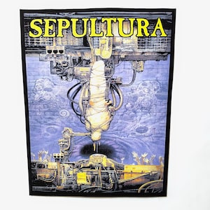 May include: A black patch with the band name "SEPULTURA" in yellow lettering. The image is a detailed, surreal illustration in blue, grey, and yellow, showing a mechanical structure and a figure wrapped in bandages.