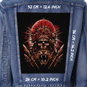 May include: A blue denim jacket featuring a large rectangular back patch with a graphic of a skull wearing a rose headdress above a roaring jaguar, flanked by two spears. The patch measures 32 cm by 36 cm, or 12.6 inches by 14.2 inches.