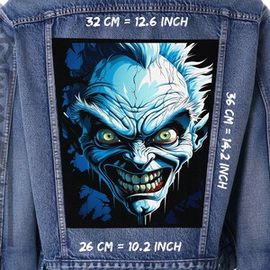 Könnte beinhalten: Eine blaue Jeansjacke mit einem großen, bunten Patch auf dem Rücken. Der Patch zeigt eine gruselige, blauhäutige Kreatur mit einem breiten, zahnigen Grinsen. Der Patch ist 32 cm breit, 36 cm hoch und 26 cm tief.