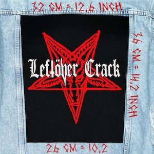 Peut inclure: Veste en jean bleu clair avec un grand écusson noir orné d'un pentagramme rouge et des mots "Leftöher Crack" en lettres gothiques blanches. L'écusson mesure 32 cm sur 36 cm.