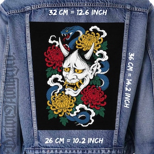 May include: A blue denim jacket featuring a large rectangular back patch with a graphic of a white Hannya mask, a blue snake, and red and yellow chrysanthemums. The patch measures 12.6 inches by 14.2 inches, with a 10.2 inch base width.