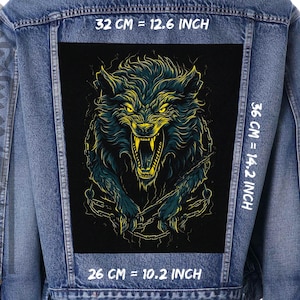 Könnte beinhalten: Eine schwarze Jeansjacke mit einem großen, bunten Wolf-Grafik-Patch auf der Rückseite. Der Patch ist 32 cm breit, 36 cm hoch und 26 cm tief. Der Wolf knurrt mit offenem Maul und hat gelbe Augen. Der Patch ist von einem schwarzen Rand umgeben.