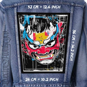 May include: A denim jacket with a large, rectangular patch featuring a colorful oni mask design. The mask is red, blue, yellow, and white, with dimensions of 26 cm by 32 cm. The jacket's back has a distressed look.