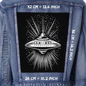 May include: A denim jacket with a black patch showing a white illustration of a UFO with light rays and stars. The patch measures 32 cm wide, 36 cm high, and 26 cm across.