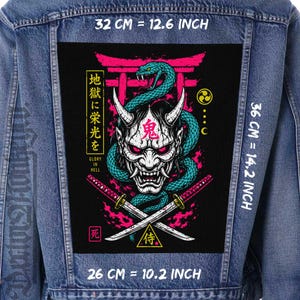 May include: A blue denim jacket featuring a large rectangular back patch with a graphic of a white oni mask, a teal snake, and two crossed katanas. The design includes pink flames, a torii gate, and text reading Glory in Hell. Dimensions are 12.6 inches by 14.2 inches.