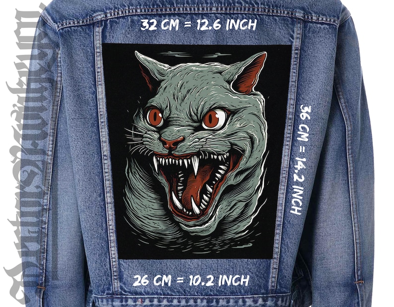 Pu&ograve; includere: Un'illustrazione in bianco e nero di un gatto che ringhia con gli occhi rossi. L'immagine &egrave; stampata su una giacca di jeans con testo bianco che recita "32 CM = 12.6 INCH", "36 CM = 14.2 INCH" e "26 CM = 10.2 INCH".