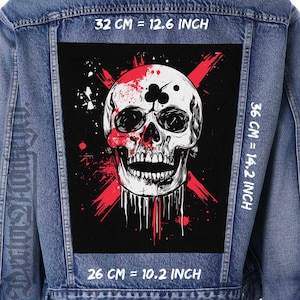 May include: A denim jacket with a large black patch featuring a detailed skull design. The skull is white with red accents and a playing card club symbol. The patch measures 12.6 inches by 14.2 inches and 10.2 inches.