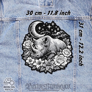 Peut inclure: Un écusson thermocollant noir et blanc représentant un rhinocéros entouré de fleurs, d'un croissant de lune et d'étoiles. Le patch mesure 30 cm sur 31 cm. Les mots "IRON ON PATCH" sont également visibles.