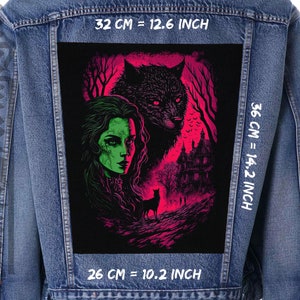 May include: A denim jacket with a black patch featuring a woman with green hair and a wolf. The patch has a pink and red background with a haunted house in the background. The text "32 CM = 12.6 INCH", "36 CM = 14.2 INCH", and "26 CM = 10.2 INCH" is printed on the jacket.
