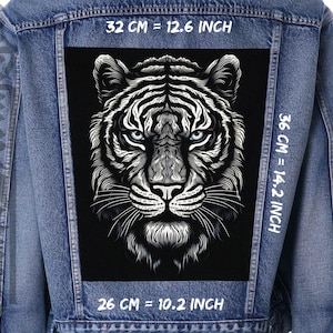 Könnte beinhalten: Ein schwarz-weißes Tigerkopf-Motiv auf einem schwarzen Patch, aufgenäht auf eine blaue Jeansjacke. Der Patch ist 32 cm breit und 36 cm hoch.