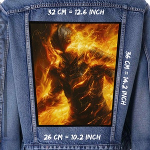 Op de afbeelding: Spijkerjasje met een groot, rechthoekig embleem op de rug. Het embleem toont een vurige figuur in vlammen. De patch is 32 cm breed en 36 cm hoog.