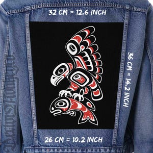 Könnte beinhalten: Eine blaue Jeansjacke mit einem großen rechteckigen schwarzen Aufnäher auf der Rückseite. Der Aufnäher zeigt einen stilisierten Adler, der einen Fisch fängt, in Rot, Weiß und Schwarz. Text gibt Maße von 32 cm = 12,6 Zoll, 36 cm = 14,2 Zoll und 26 cm = 10,2 Zoll an.