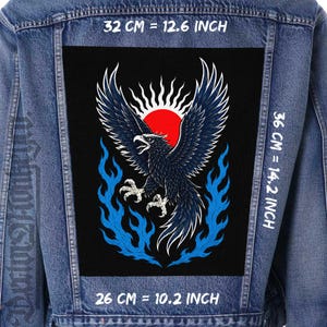 May include: A denim jacket with a large black patch featuring a detailed illustration of a dark blue eagle with outstretched wings, a red sun, and blue flames. The patch measures 32 cm wide, 36 cm high, and 26 cm long.