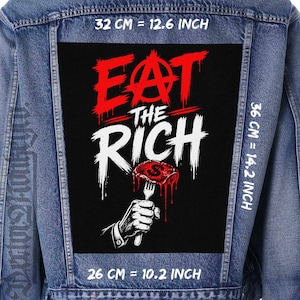 May include: A denim jacket with a large black patch featuring the text "EAT THE RICH" in red and white. The patch includes a graphic of a hand holding a steak with a dollar sign on a fork. Patch dimensions are 32 cm by 36 cm.