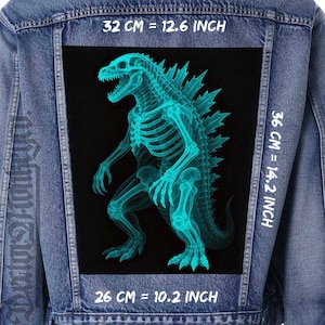 Può includere: Giacca di jeans con una toppa rettangolare di grandi dimensioni con un disegno di scheletro di Godzilla color turchese su sfondo nero. La toppa misura 32 cm di larghezza, 36 cm di altezza e 26 cm di lunghezza.