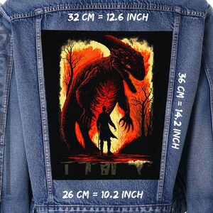 Peut inclure: Une veste en jean avec un grand patch au dos. Le patch représente un dinosaure rouge sur un fond de feu et le texte "IT" en blanc. Le patch mesure 36 cm sur 26 cm, soit 14,2 pouces sur 10,2 pouces.