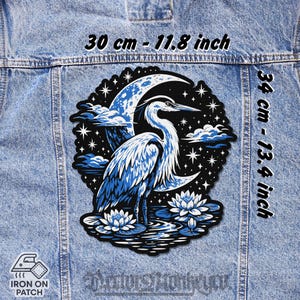 Peut inclure: Écusson thermocollant avec un héron bleu devant une lune et un ciel étoilé. Le patch mesure 30 cm sur 34 cm. Le motif comprend des nénuphars et des nuages.