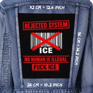 Puede incluir: Chaqueta vaquera con un parche negro grande con el texto "REJECTED SYSTEM", un código de barras tachado y las palabras "ICE", "NO HUMAN IS ILLEGAL" y "FUCK ICE" en rojo y blanco. Medidas: 32 cm, 36 cm y 26 cm.