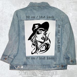 Pode incluir: Ilustração em preto e branco de uma mulher usando um chapéu. A ilustração é impressa em um remendo branco de 36 cm de altura e 26 cm de largura. O remendo está preso a uma jaqueta de jeans azul.