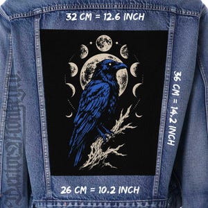 Può includere: Una giacca di jeans blu con una grande toppa rettangolare sul retro su sfondo nero. La toppa raffigura un corvo blu appollaiato su un ramo davanti a una luna piena circondata dalle fasi lunari. Le dimensioni sono 32 cm per 36 cm.