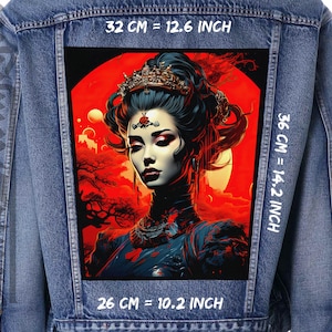 May include: A denim jacket with a large patch on the back featuring a digital illustration of a woman with dark hair and a crown, set against a red background with a moon and stars. The patch measures 32 cm wide by 36 cm tall.