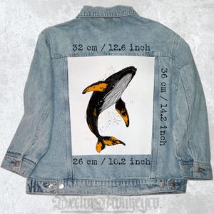 Può includere: Giacca di jeans blu chiaro con grafica di balena. La balena è nera e arancione, con dettagli bianchi. La grafica misura 32 cm di larghezza, 36 cm di altezza e 26 cm di lunghezza. La giacca ha un design classico.