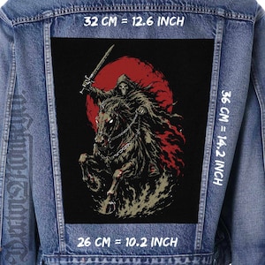 Può includere: Una giacca di jeans blu con una grande toppa rettangolare sul retro raffigurante uno scheletro incappucciato a cavallo che impugna una spada davanti a una luna rossa. La toppa misura 32 cm per 36 cm, con una larghezza inferiore di 26 cm.