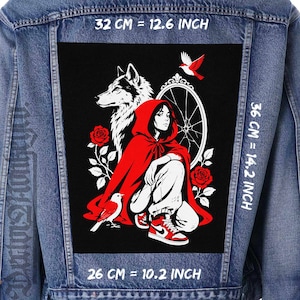 Könnte beinhalten: Jeansjacke mit einem großen schwarzen Aufnäher mit einer Grafik einer Person in rotem Kapuzenmantel, einem Wolf und Vögeln. Der Aufnäher ist 32 cm breit, 36 cm hoch und 26 cm lang.