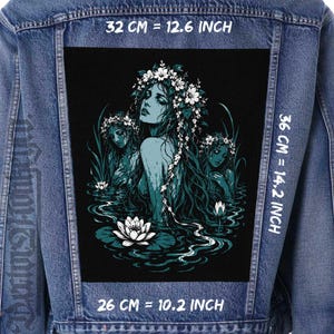 Peut inclure: Une veste en jean bleu avec un grand écusson rectangulaire au dos représentant trois personnages couronnés de fleurs émergeant de l'eau avec des lotus blancs. L'écusson mesure 32 cm par 36 cm par 26 cm.