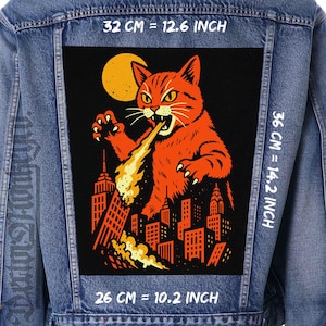 Puede incluir: Chaqueta vaquera con un parche grande que muestra un gato naranja respirando fuego sobre un horizonte urbano. El parche mide 32 cm de ancho por 36 cm de alto. El gato está sobre un fondo negro con una luna amarilla.