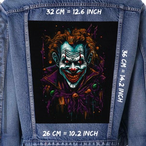 May include: A denim jacket with a black patch featuring a colourful illustration of a grinning clown with purple and green accents. The patch is 32 cm wide, 36 cm tall, and 26 cm deep.