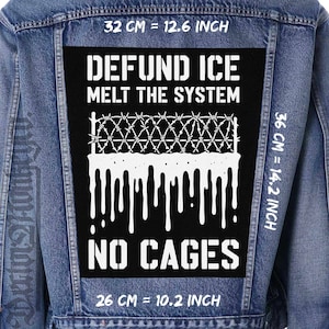 May include: A denim jacket with a large black patch. The patch has white text reading "DEFUND ICE MELT THE SYSTEM" and "NO CAGES." It features a barbed wire design and dripping white paint. Measurements are 32 cm, 36 cm, and 26 cm.