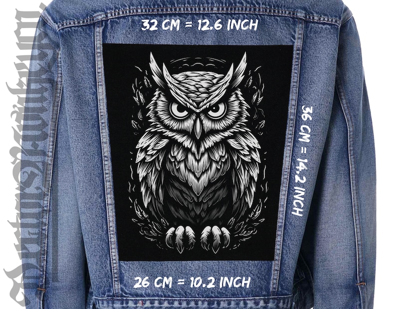 May include: A denim jacket featuring a large, black and white owl patch. The patch measures 32 cm wide, 36 cm tall, and 26 cm long. The owl design has detailed feathering and piercing eyes, creating a striking contrast against the jacket's blue denim.