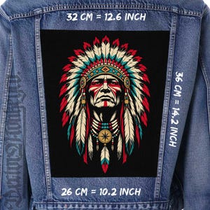 Könnte beinhalten: Eine blaue Jeansjacke mit einem großen rechteckigen Aufnäher auf der Rückseite. Der Aufnäher zeigt eine Grafik einer Person mit Federschmuck in Rot, Weiß und Türkis. Der Text gibt Maße von 32 cm, 36 cm und 26 cm an.